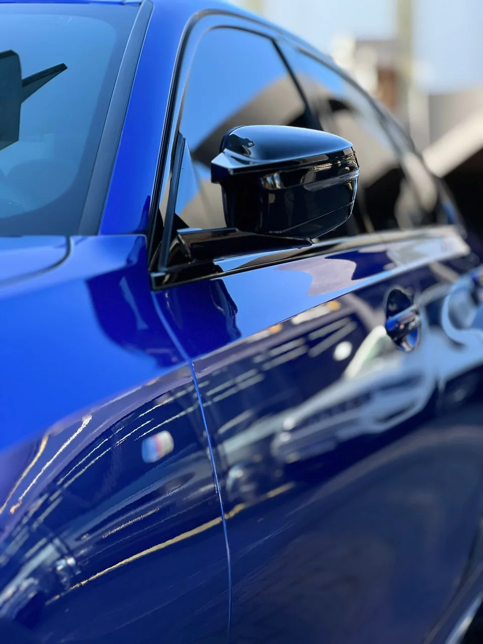 Detalhe da pintura e do retrovisor de um BMW azul