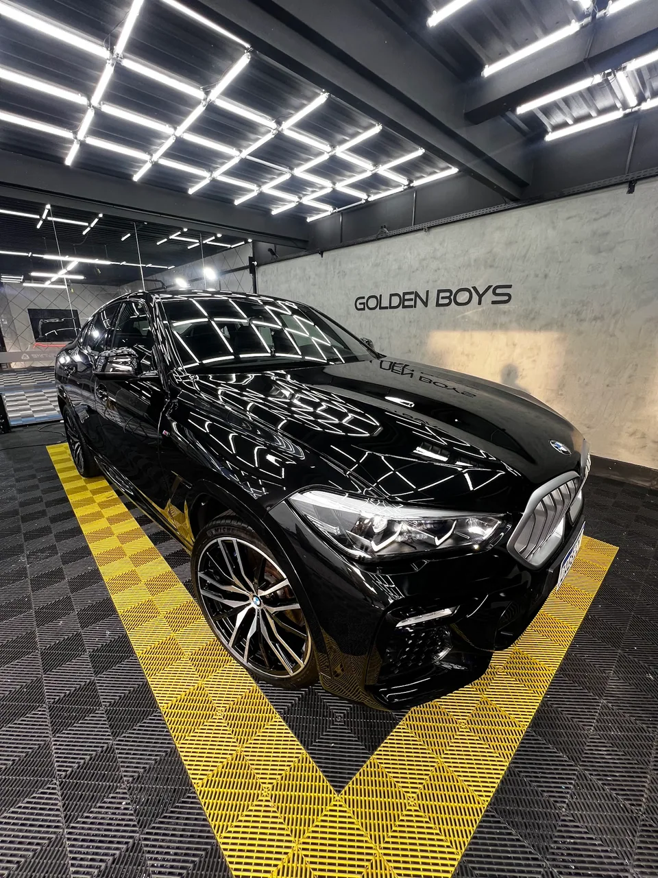 Veículo preto na Golden Boys Detailers, com reflexos das luzes geométricas na pintura
