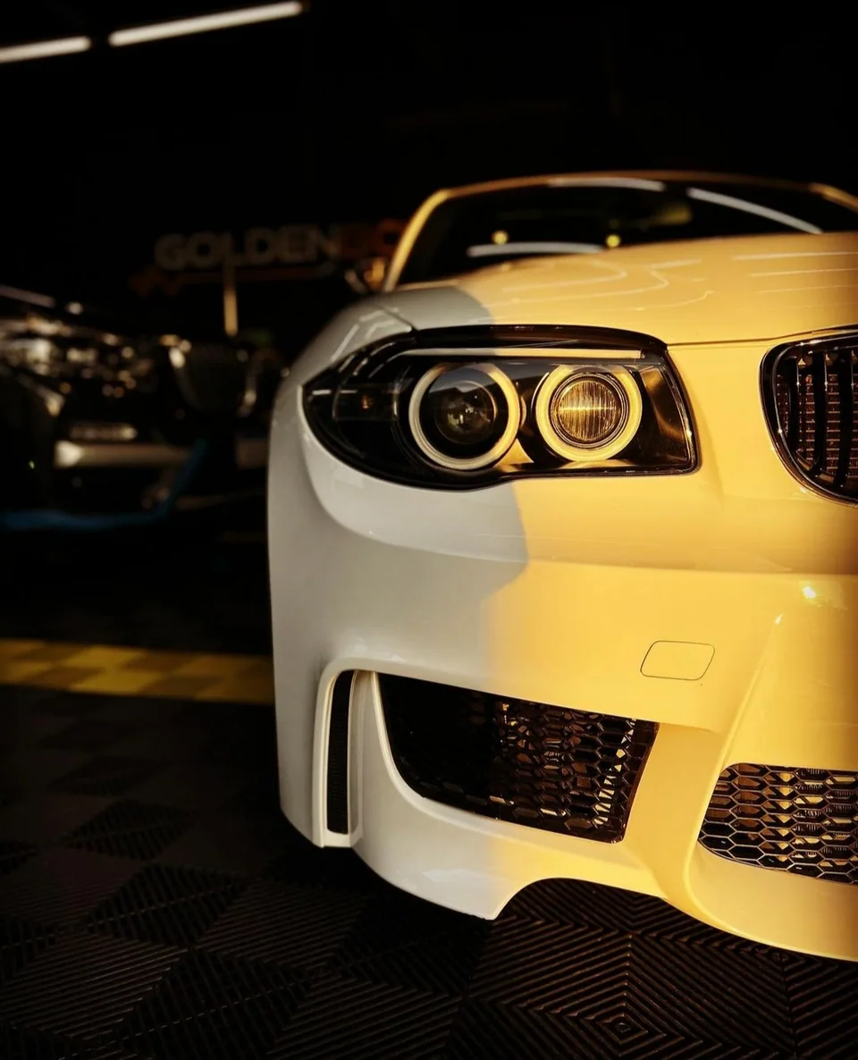Farol e pintura de um BMW branco sob iluminação quente